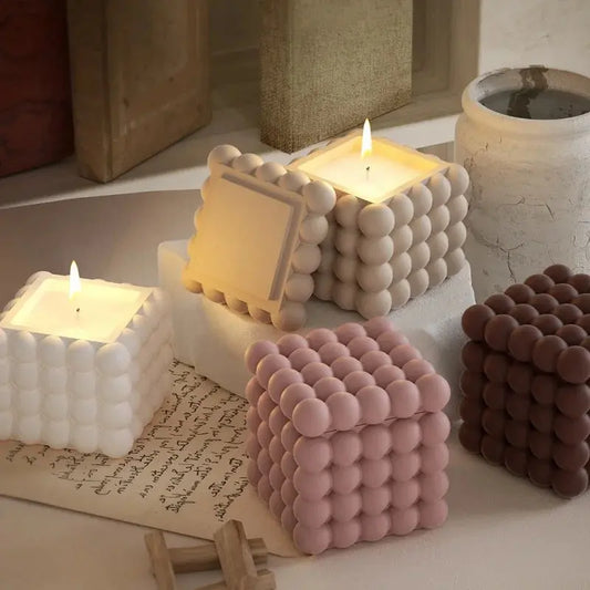 Beautiful 3D bubble cube candles in neutral tones - cream, pink, and brown - displayed on a minimalist surface with warm candlelight, showcasing professional DIY candle making results